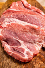 a raw meat, pig neck on a wooden background