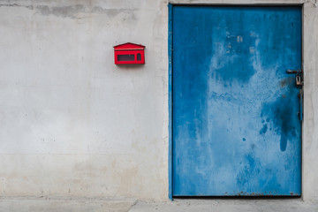The concrete wall, a red mailbox and a metal door.