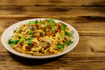 Pasta with mushrooms and tomato sauce on wooden table