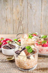 Set various fruit overnight oatmeal. Oats porridge with strawberry, bananas, chocolate, nuts in small portion jars. Summer breakfast oatmeal. Healthy vegan diet snack.