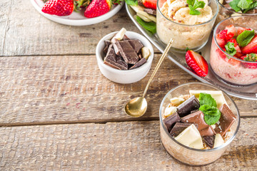 Set various fruit overnight oatmeal. Oats porridge with strawberry, bananas, chocolate, nuts in small portion jars. Summer breakfast oatmeal. Healthy vegan diet snack.