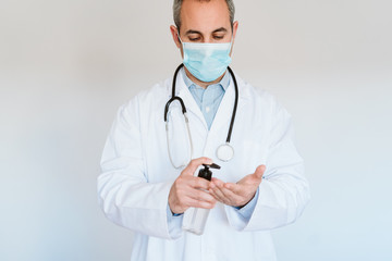 caucasian doctor wearing protective mask and gloves indoors. Holding an alcohol gel or antibacterial disinfectant. Hygiene and corona virus concept