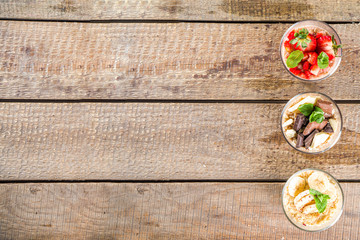 Set various fruit overnight oatmeal. Oats porridge with strawberry, bananas, chocolate, nuts in small portion jars. Summer breakfast oatmeal. Healthy vegan diet snack.