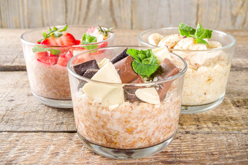 Set various fruit overnight oatmeal. Oats porridge with strawberry, bananas, chocolate, nuts in small portion jars. Summer breakfast oatmeal. Healthy vegan diet snack.