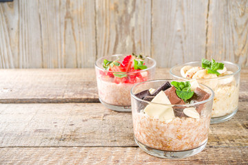 Set various fruit overnight oatmeal. Oats porridge with strawberry, bananas, chocolate, nuts in small portion jars. Summer breakfast oatmeal. Healthy vegan diet snack.