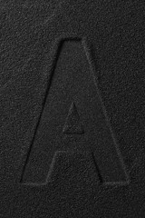 Imprint of a letter squeezed out on black sand.