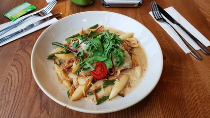 Pasta with sauce and green salad on a large white plate