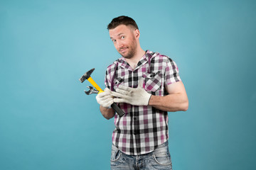 Dirty hard worker in a clever shirt with tools in his hands smiles slyly