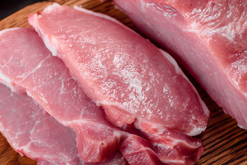 Fresh pieces pork ready to cook on a dark background in the kitchen