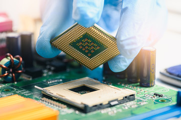 The technician is laying a CPU on the socket of the computer motherboard. the concept of computer,...