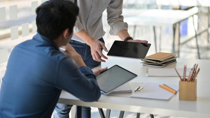 Two asian men using a tablet. They consulted the job to present clients in a contemporary office.