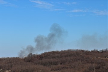 Fototapeta na wymiar Gray smoke spreads over the field.
