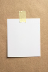 Blank polaroid photo frame with soft shadows and yellow scotch tape on craft cardboard paper background as template for graphic designers presentations, portfolios etc.