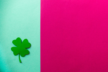 one green clover on a blue and rose background, flat lay, copy text, vertical separation.