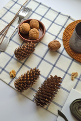 Fototapeta na wymiar Walnuts, chocolate and cones, cutlery on a kitchen towel on a white background