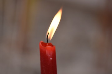 Burning red candle with blurred background