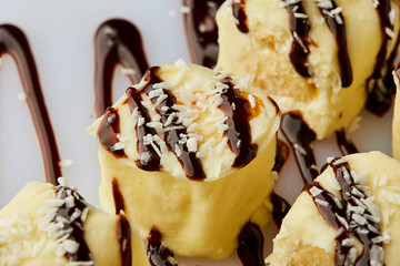 Delicious healthy homemade dessert of bananas, chocolate and cream cheese or ricotta. Banana rolls on a white plate. Treats for kids