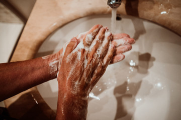 Middle-aged woman washing her hands with soap and water to avoid contagion of the coronavirus. Health risk prevention. Healthcare