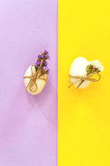 Trending white Easter eggs with flowers on a lilac and yellow background. Minimal concept