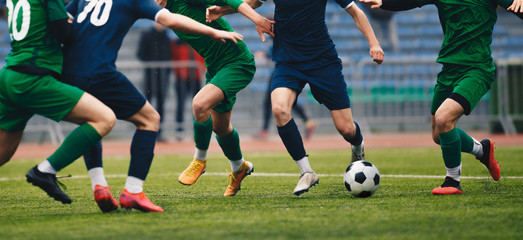 Soccer football player dribbling a ball and kick a ball during match in the stadium. Footballers in...
