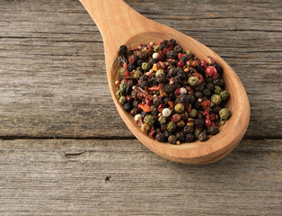 mix of dry balls of various peppers in a wooden spoon