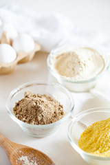 Various gluten free flour corn,sesame,oat,coconut in bowl on white background.Alternative to wheat flour for keto paleo diet.Healthy eating,dieting,balanced food concept.Vertical orientation,top view