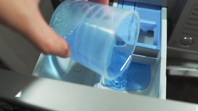 Liquid Soap Being Poured Into Washing Machine Compartment