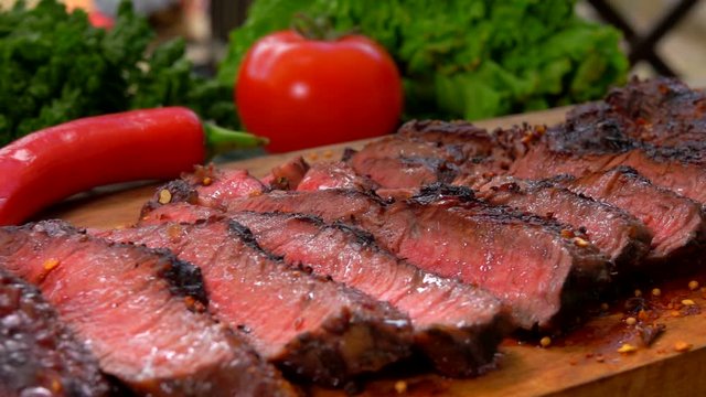 Panorama movement along the prepared juicy beefsteak cut on slices on a wooden board