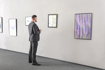 Obraz premium Young man at exhibition in modern art gallery