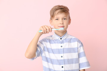 Cute little boy with toothbrush on color background