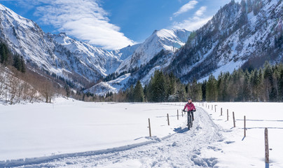 nice senior woman riding her electric mountainbike on a sunny winter day in the Allgau alps near Oberstdorf, Bavaria, Germany