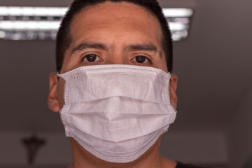 Hombre latino con mascarilla trabajando en oficina por corona virus