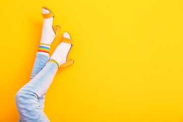 Legs of young woman in socks and sandals on color background