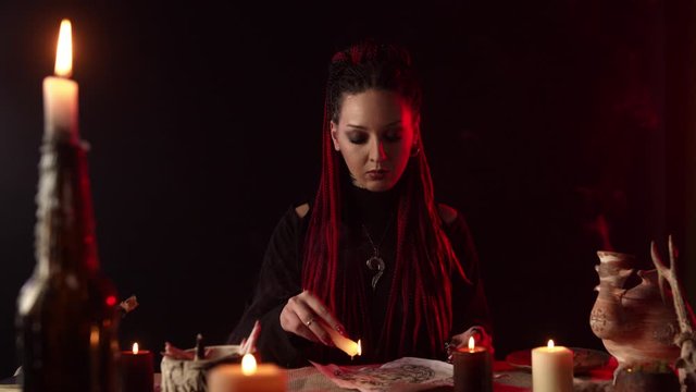 Witch with candles dripping wax on pentagram in dark room