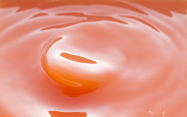 a swirling wave on the surface of grapefruit juice.