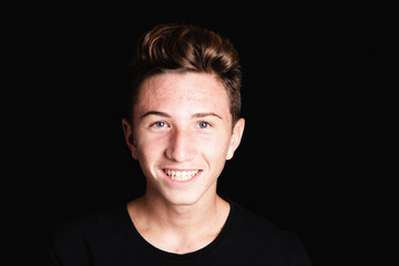 cheerful teenager boy face with acne on black background