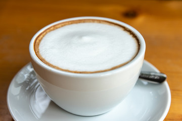 A cup of hot cappuccino coffee in white coffee cup.