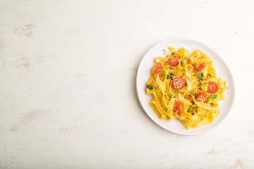 Reginelle pasta with tomato, eggs, sesame and microgreen sprouts on a white wooden background. Top view, copy space.