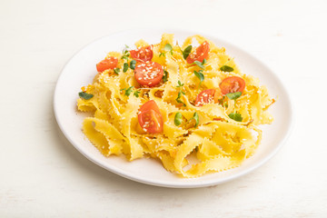 Reginelle pasta with tomato, eggs, sesame and microgreen sprouts on a white wooden background. Side view.