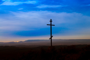 Black religion symbol silhouette Jesus Christ wooden cross on a background with colorful mountain sunset, Easter concept.