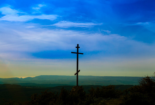 Black religion symbol silhouette Jesus Christ wooden cross on a background with colorful mountain sunset, Easter concept.
