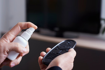 man disinfecting the TV remote control