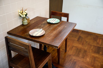 Wooden dining table with crockery and flower vase in restaurant