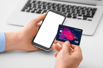 Man with mobile phone and credit card at table, closeup