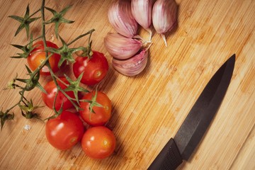 Pomodorini e aglio su un tagliere di legno