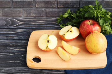 Slicing apples on a light wooden board, a dark wooden background