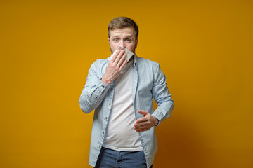 Man is about to cough or sneeze and scared covers mouth with a napkin. Concept of the spread of the...