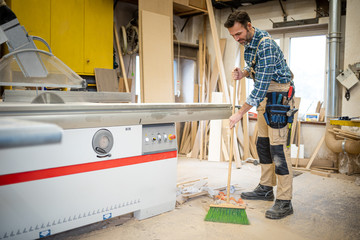 Craftsman cleans his carpentry workshop after work