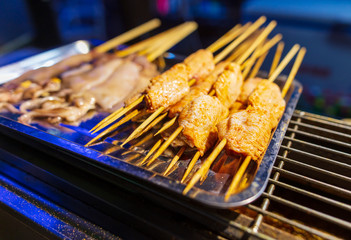 Chicken on wooden sticks for grilling.