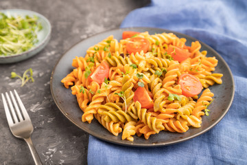 Tortiglioni semolina pasta with tomato and microgreen sprouts on a black concrete background. Side view, selective focus.